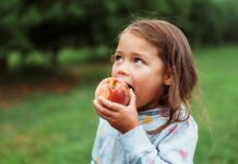 시민의 여가와 웃음이 함께하는 주말! 파주시, 다목적체육관 ‘가족 물놀이장’ 운영 A young girl eating a fresh peach outdoors.